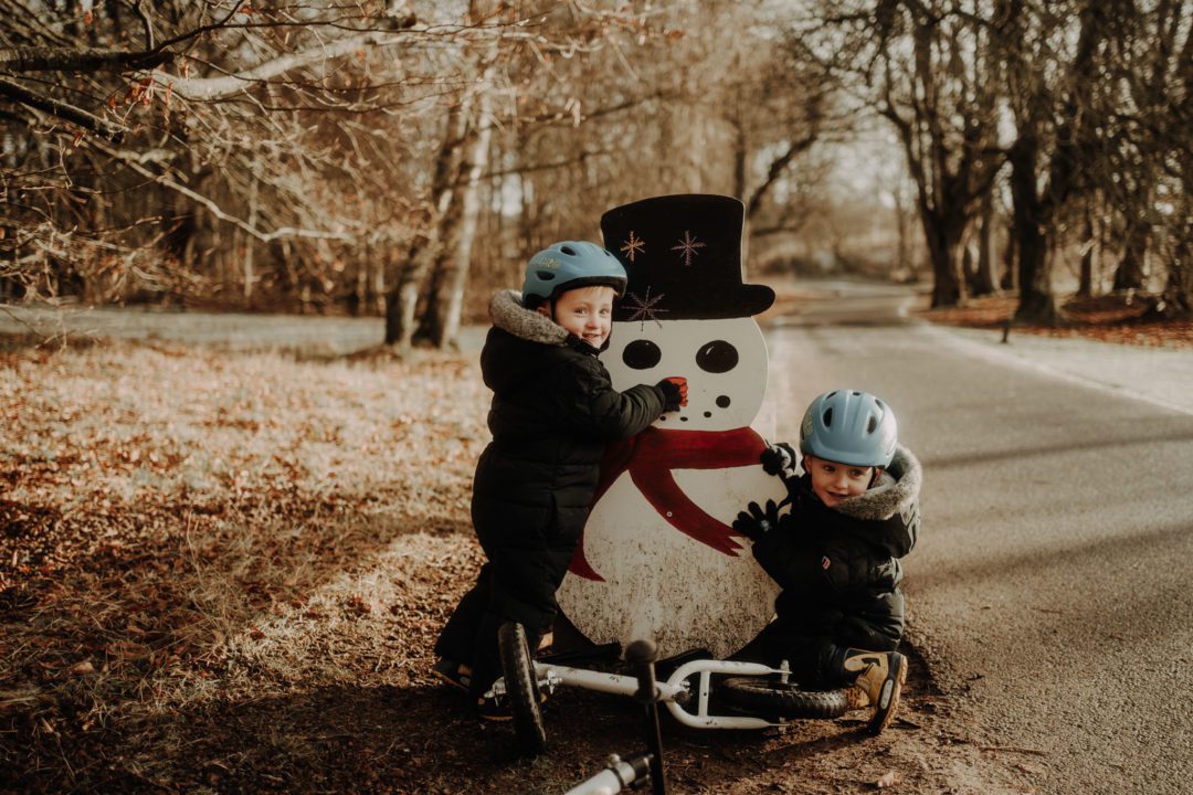 twin boys posing with snowman