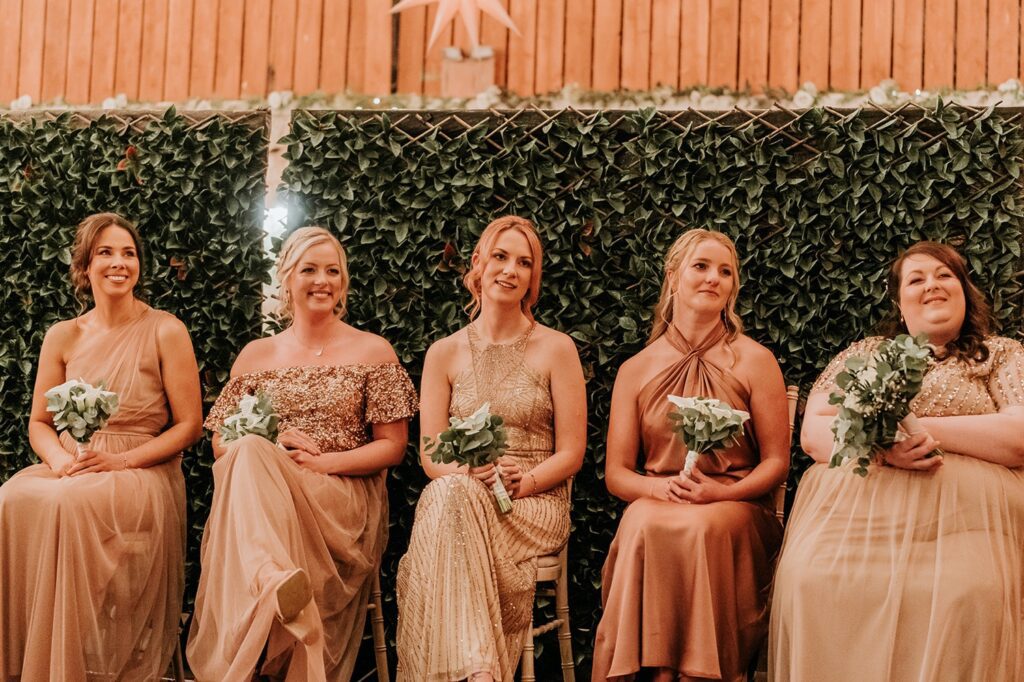 Bridesmaids sitting down in pink dresses at a wedding ceremony