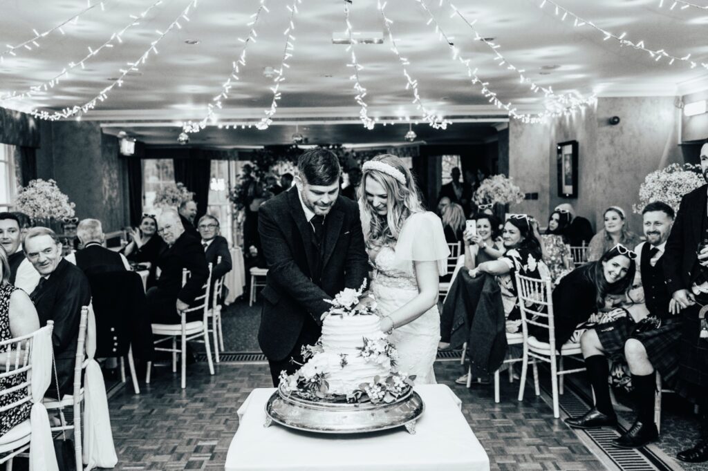 Bridal couple cutting their cake at Banchory Lodge Hotel. Black and white image