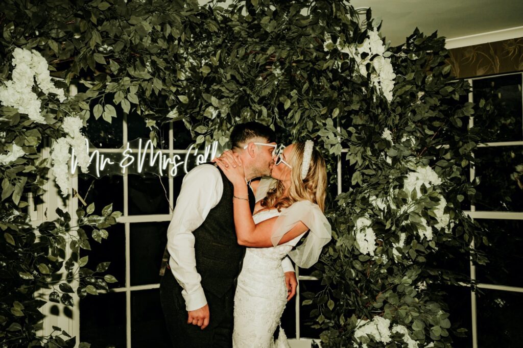 Couple in front of greenery garland and neon sign at Banchory Lodge Hotel