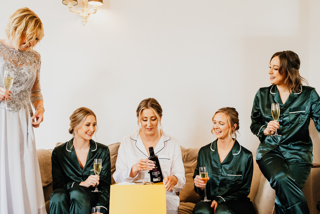 bride and bridemaids sitting on sofa opening gifts