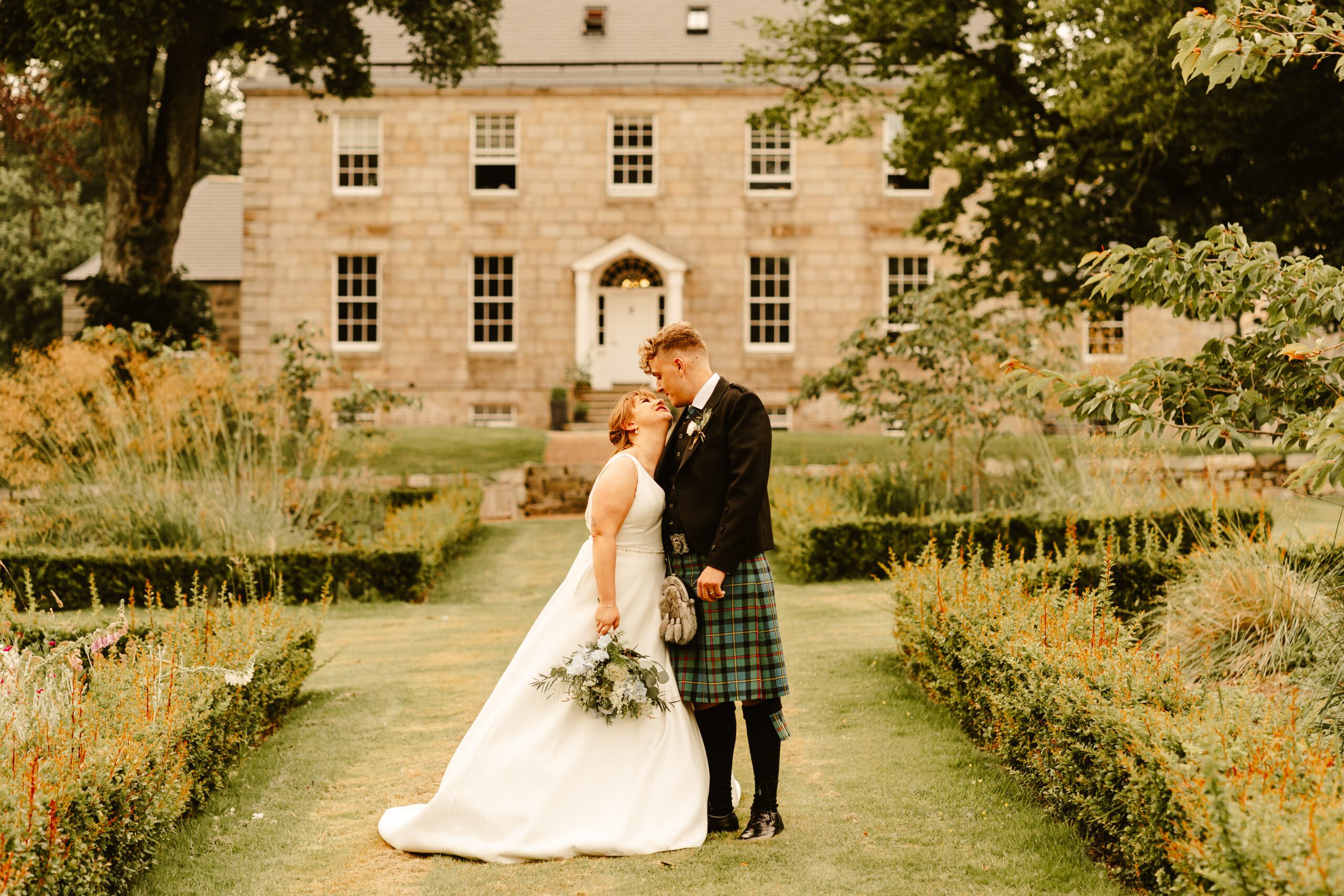 Couple embrace on the grass on their wedding day at Elrick House wedding venue