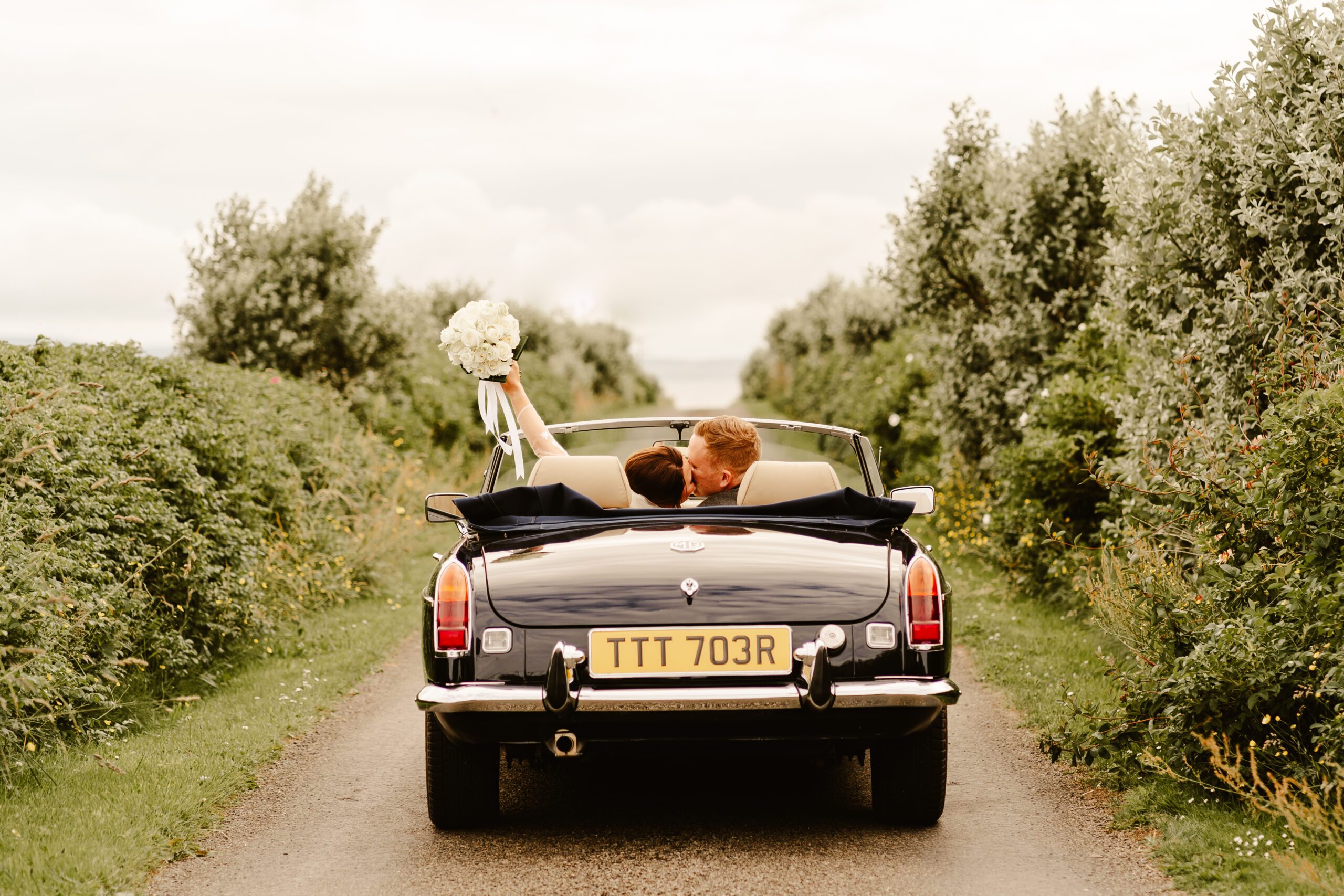 Couple riding in a convertible during their Scottish destination wedding in Orkney