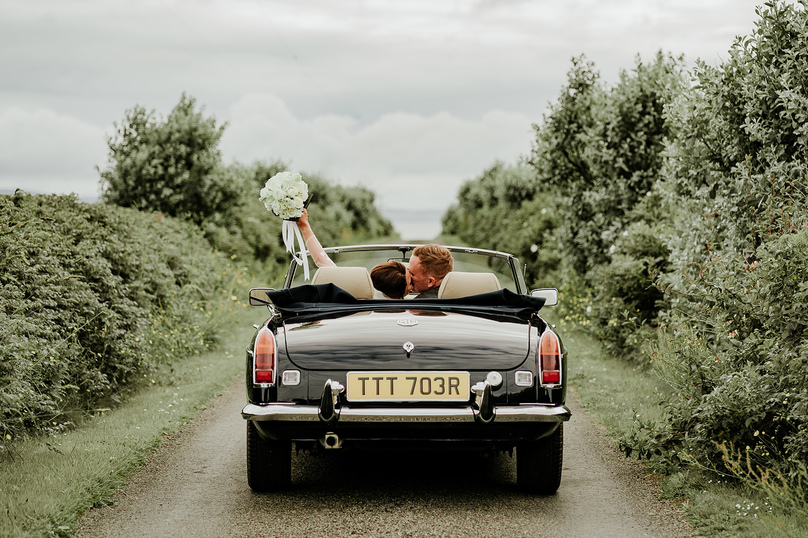 Couple riding in a convertible during their Scottish destination wedding in Orkney