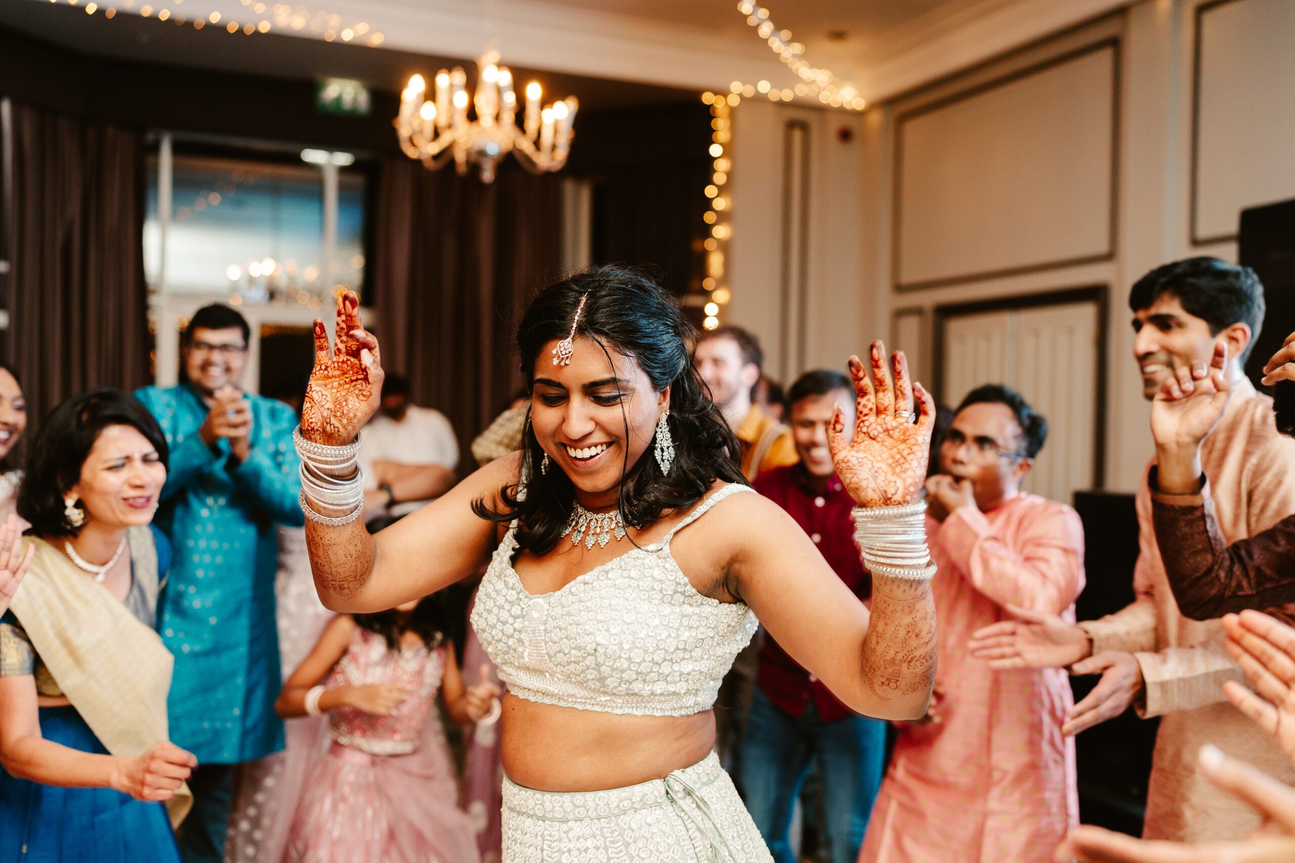 Bride wears white sequinned lehenga as she dances on the dance floor at Ardoe House