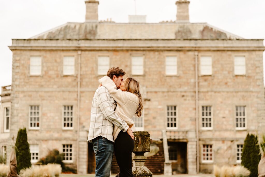 couple kiss in front of house during pre wedding shoot at haddo house