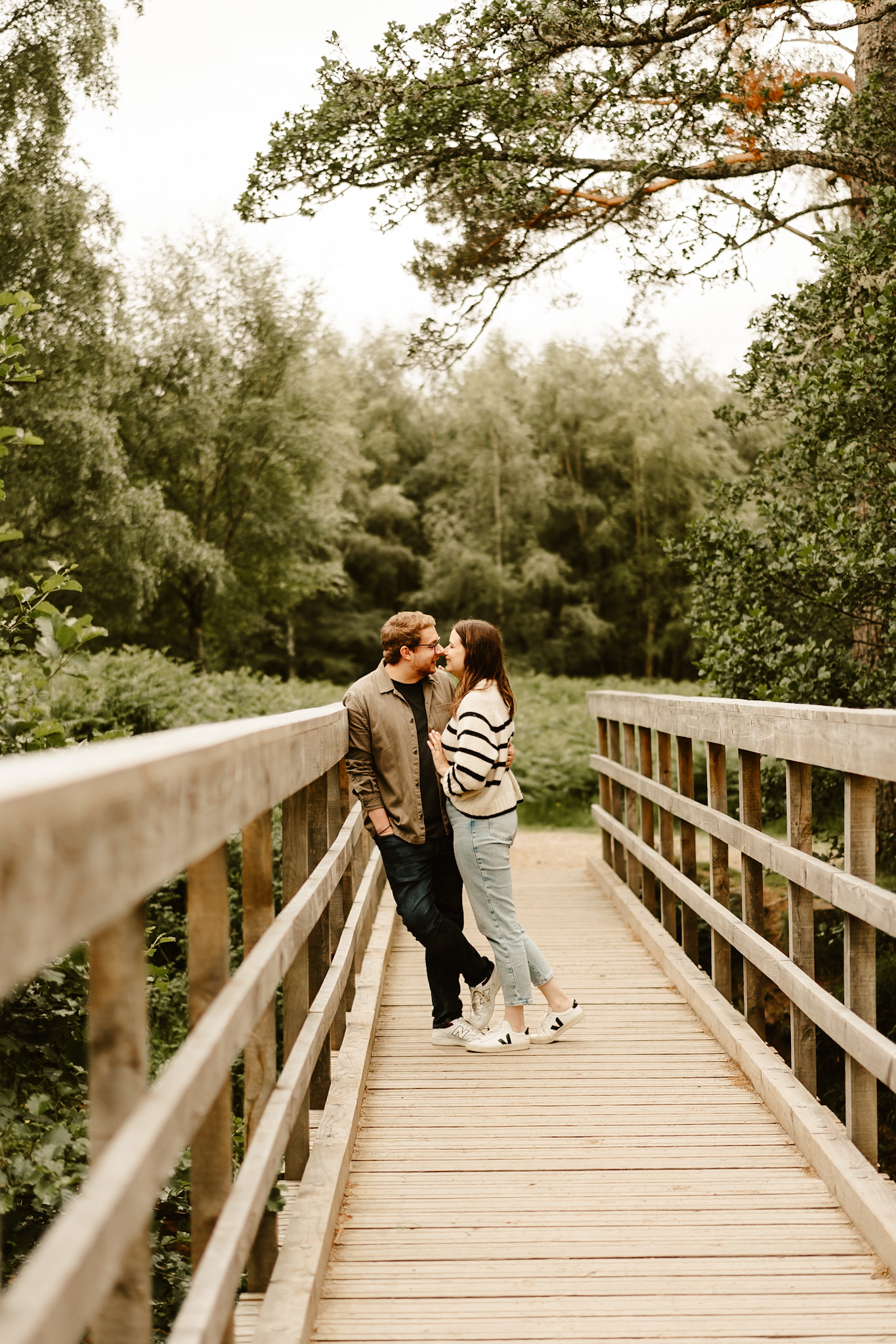 Couple lkiss on bridge at loch. Morlich Scottish engagement photoshoot