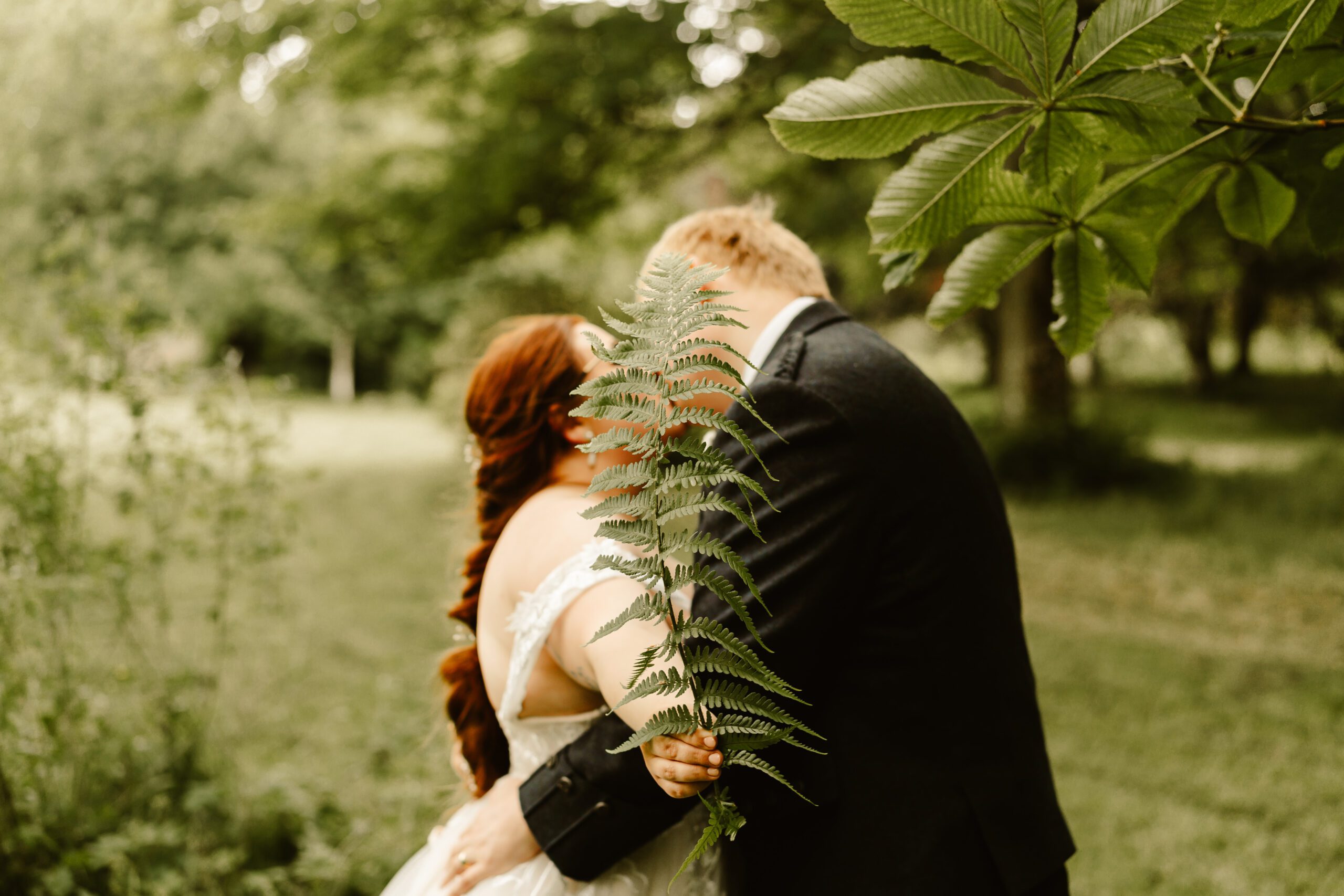 bride and groom kiss outside behind a fern leaf at haddo house wedding