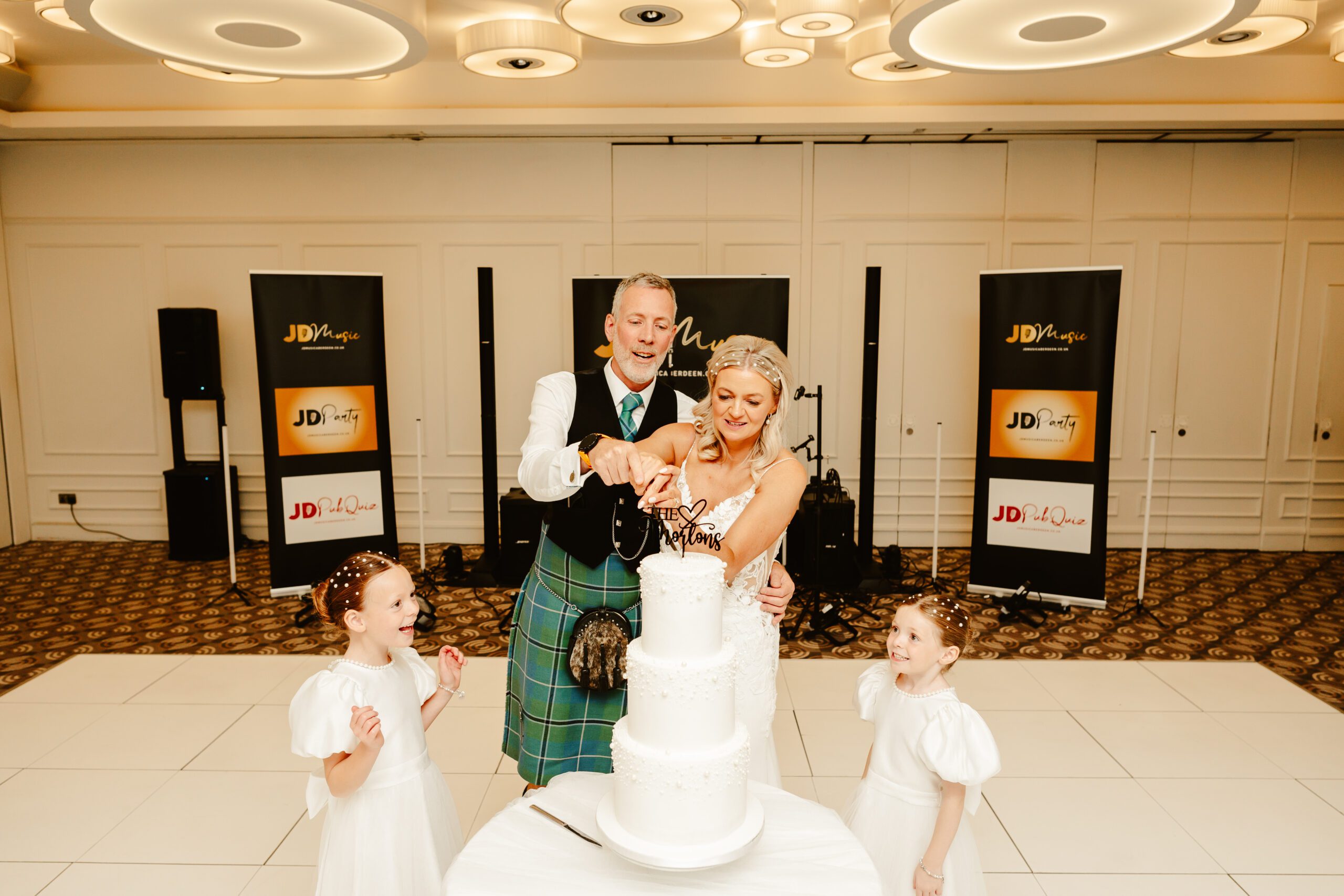 bride and groom cut their wedding cake with their daughters at the chester hotel