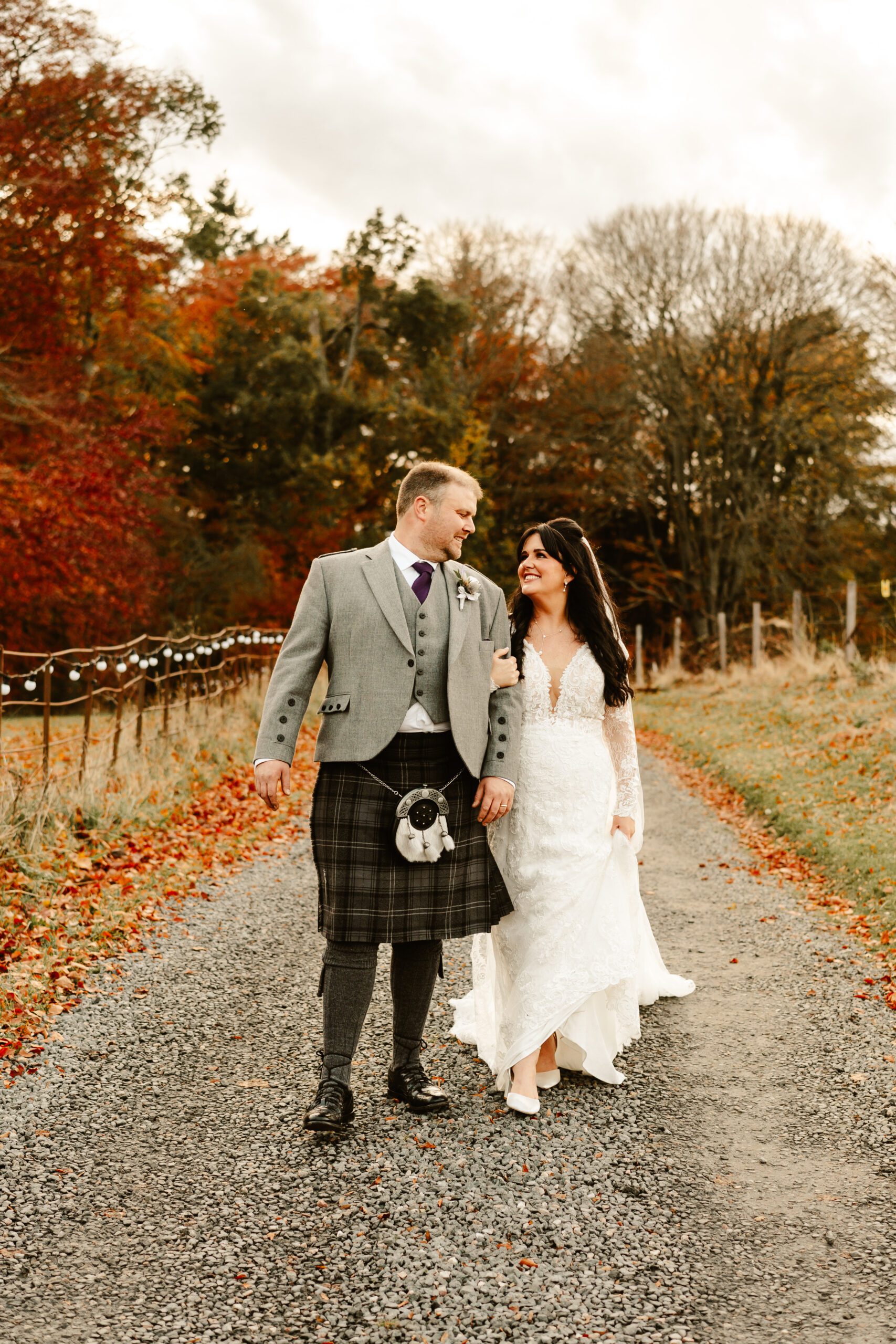 bride at groom walking outdoors at Logie country house wedding during autumn